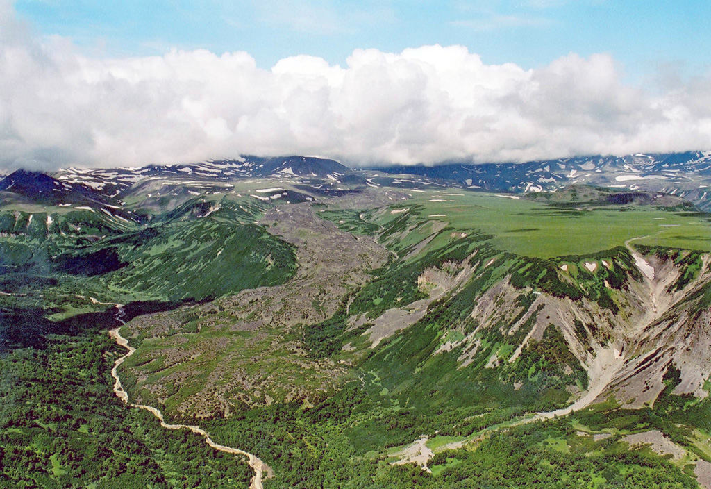 The Kireunsky lava flow erupted from a vent on the eastern side of the Alney-Chashakondzha volcanic massif (background) about 2,600 years ago. The vent is located in the divide between the Kirevna (far right) and Pravaya Kirevna (left foreground) rivers.  Copyrighted photo by Adam Kirilenko, 2002.