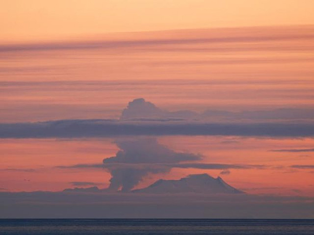 A plume rises above Fourpeaked during its first observed eruption, on 7 September 2006, as seen from Main Street in Homer, across Cook Inlet. The plume rose to a maximum height of 6 km and resulted in a trace of ashfall at Nonvianuk Lake outlet (110 km WNW) and near Homer (150 km NE). The eruption produced a 1-km-long fissure that extended north from the summit. Copyrighted photo by Lanny Simpson, 2006 (courtesy of USGS/AVO).