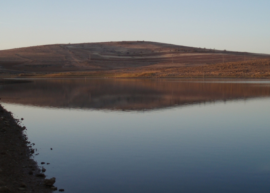 Columba volcano, the youngest known vent of the dominantly Pliocene Calatrava Volcanic Field, rises above the Jabalón reservoir (foreground). The massive volcanic field covers an area of over 5,000 km2 and contains more than 300 cones, maars, and lava domes. This field is mostly of Pliocene or late-Pleistocene age, although late-stage phreatomagmatic activity at Columba volcano was dated at the mid-Holocene. Fumarolic activity was recorded in the Sierra de Valenzuela area during the 16th-18th centuries. Photo by Rafael Becerra Ramírez, 2006 (Universidad de Castilla-La Mancha).