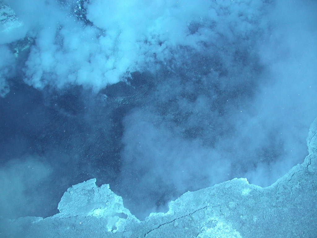 A plume rises from a vent at about 400 m depth on Daikoku seamount in this close-up view only about a few meters across. During a NOAA expedition in 2006 scientists observed a convecting, black pool of liquid sulfur with a partly solidified, undulating sulfur crust. The summit of lies along an E-W-trending ridge SE of Eifuku submarine volcano and rises to within about 300 m of the ocean surface. Image courtesy of Submarine Ring of Fire 2006 Exploration, NOAA Vents Program.