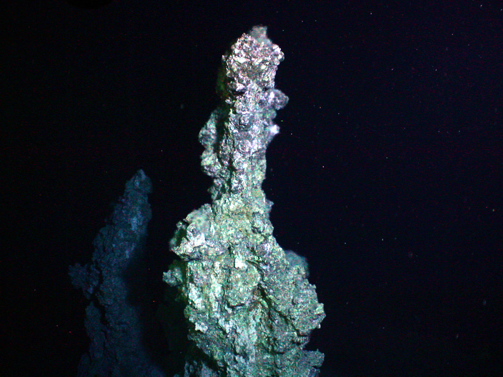 Diffuse hydrothermal venting and sulfide chimneys were observed near the summit of Clark volcano during a New Zealand-American NOAA Vents Program expedition in 2005. Hot water (221°C, 430°F) was sampled at the base of this sulfide chimney, which is almost 6 m high. Clark submarine volcano lies near the lower end of the Southern Kermadec Arc and is the southernmost volcano of the submarine chain that displays known hydrothermal activity. Image courtesy of New Zealand-American Submarine Ring of Fire 2005 Exploration, NOAA Vents Program.