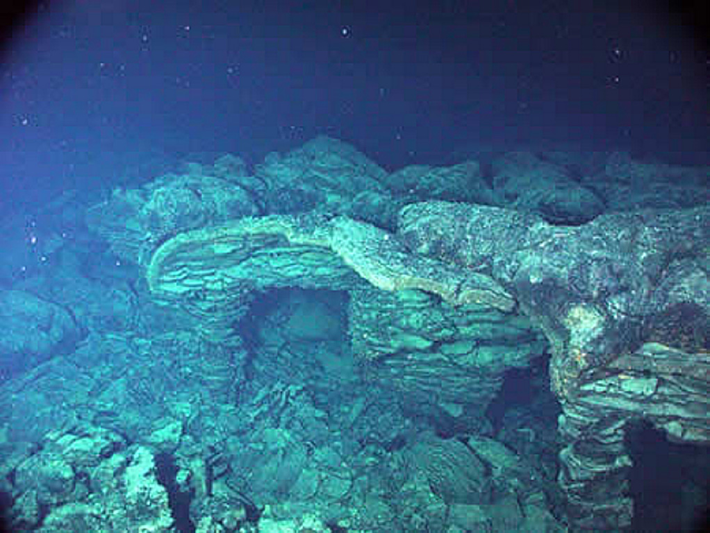 An eruption from the southern end of Axial caldera in 1998 produced this submarine lava flow that had undergone collapse, shown in this photo. Axial Seamount rises 700 m above the mean level of the central Juan de Fuca Ridge crest about 480 km W of Cannon Beach, Oregon, to within about 1.4 km of the ocean surface. The 3 x 8 km Axial caldera opens to the SE and is defined on three sides by caldera walls up to 150 m high. Hydrothermal vents colonized with biological communities are located near the caldera boundary or along the rift zones. Photo courtesy of NOAA NeMo Observatory, 2006.