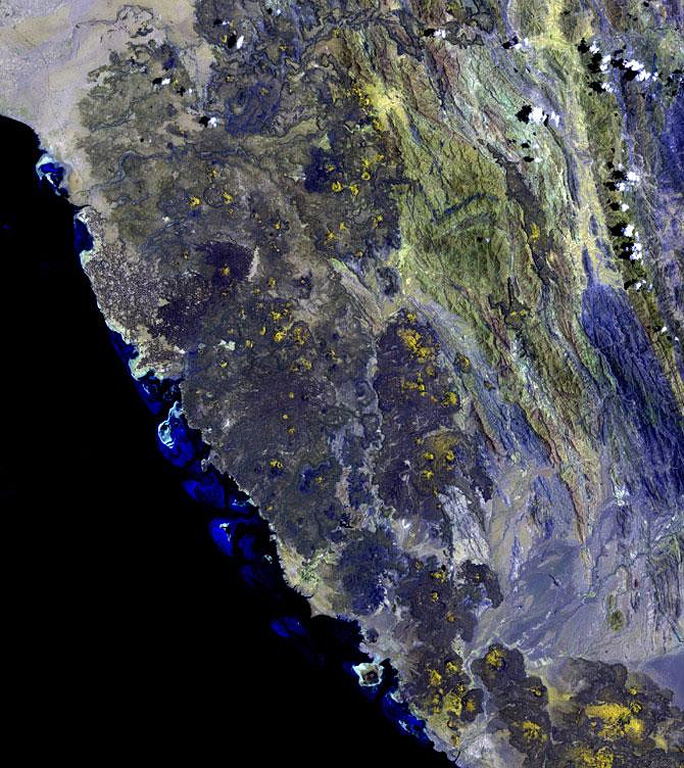The 1,800 km2 Miocene and Quaternary Harrat al Birk volcanic field extends diagonally across the center of this NASA Landsat image along the Red Sea coast. Dark-colored areas are lava fields and yellowish areas mark scoria cones and deposits. Scoria cones occur throughout the field, and a few outlying cones lie E of the main lava field.  NASA Landsat image, 2003 (USGS).