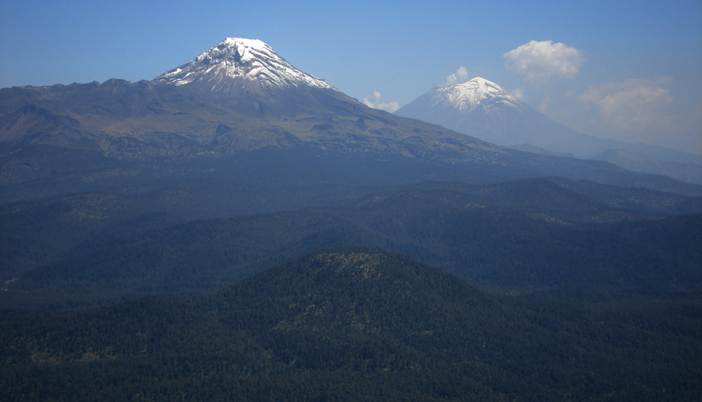 This photo looks south from Telapón volcano and shows the rounded Papayo lava dome in the foreground, with snow-capped Iztaccíhuatl (left) and Popocatépetl (right) in the background. These volcanoes, along with Telapón, and Tláloc stratovolcanoes, form a N-S-trending chain east of Mexico City and transverse to the Mexican Volcanic Belt trend. Photo by Anita Cadoux, 2007 (Instituto de Geofísica, UNAM, Mexico).