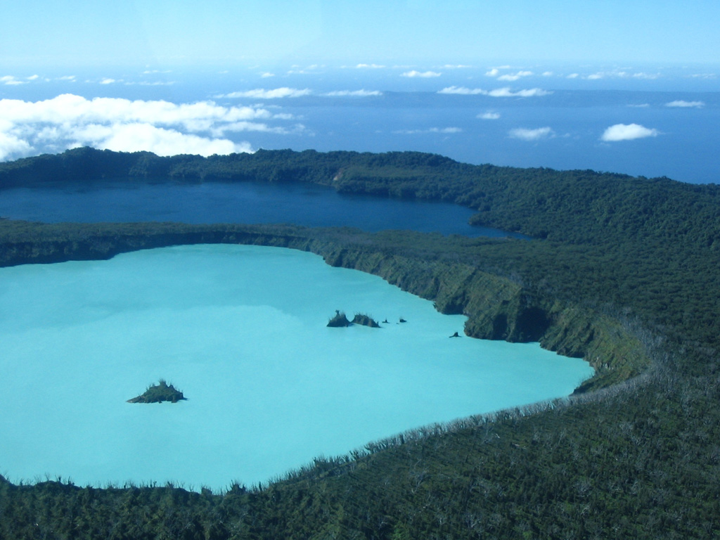 Two lakes of variable color lie with the summit caldera of Ambae volcano, as seen in this view from the W. The light blue lake in the foreground is Lake Voui (or Vui), which is enclosed in the crater of a tuff ring within the summit caldera. The dark blue Lake Manaro Lakua lies between the tuff ring and the E caldera wall. Ambae, the most voluminous volcano of the New Hebrides archipelago, forms a 16 x 38 km island. Pentecost Island appears in the background. Photo by Karoly Nemeth, 2005 (Massey University).