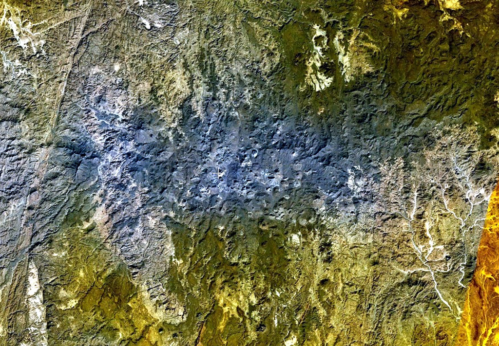 The bluish-gray area at the center of this NASA Landsat image and areas at the upper right are part of the massive Atakor volcanic field. These volcanics cover an area of 2,150 km2 and includes lava domes and abundant basaltic scoria cones and lava flows. Historical pottery has been found within lava flows in the Tahifet area, and oral traditions of the Tuareg people also suggest that eruptions were witnessed. The prominent lineament at the far left is the Inter-terrane Pan-African shear zone. NASA Landsat 7 image (worldwind.arc.nasa.gov)