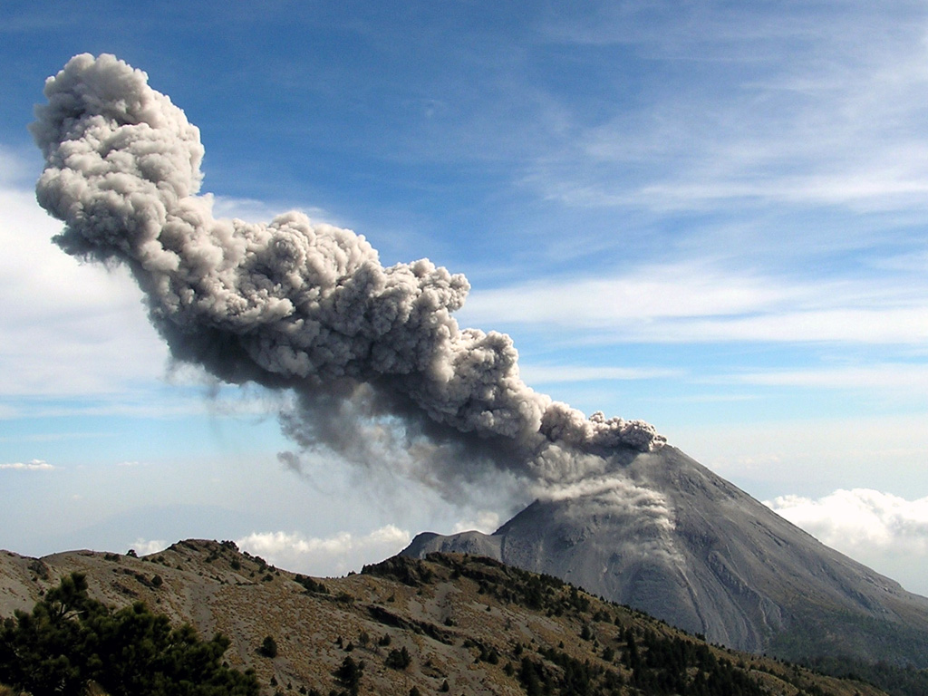 A Vulcanian explosion typical of activity at Colima is seen here from the north on 10 March 2007. Intermittent explosive eruptions with occasional lava dome growth and associated pyroclastic flows had been continuing for nearly a decade at this time.  Photo courtesy of Colima Volcano Observatory, 2007.