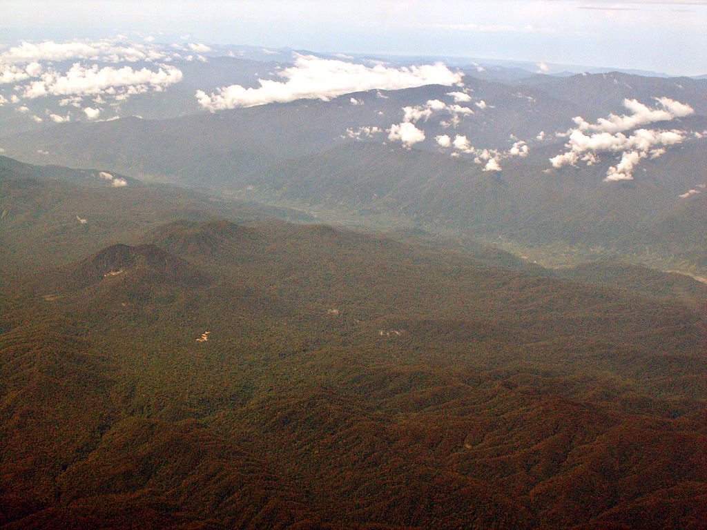 Kembar volcano, the small forested peak at left-center, is seen in this aerial view from the N. The Gayolesten fumarole field is located on the flanks of the Pleistocene volcano. It is located at the junction of two fault systems and is capped by a complex of craters and cones. Active fumaroles and hot springs are present at several locations. Copyrighted photo by Michael Thirnbeck, 2006.