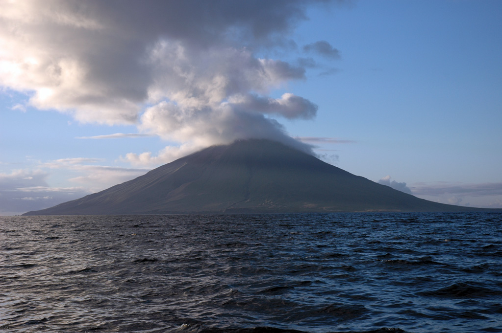 The 6 x 7 km Segula island is seen offshore from the SW. It has a prominent NNW-SSE-trending fissure that extends to sea level at both ends of the island. The summit contains a small, poorly defined caldera that has a scoria cone forming the high point of the island.  Photo by Christina Neal, 2005 (Alaska Volcano Observatory, U.S. Geological Survey).