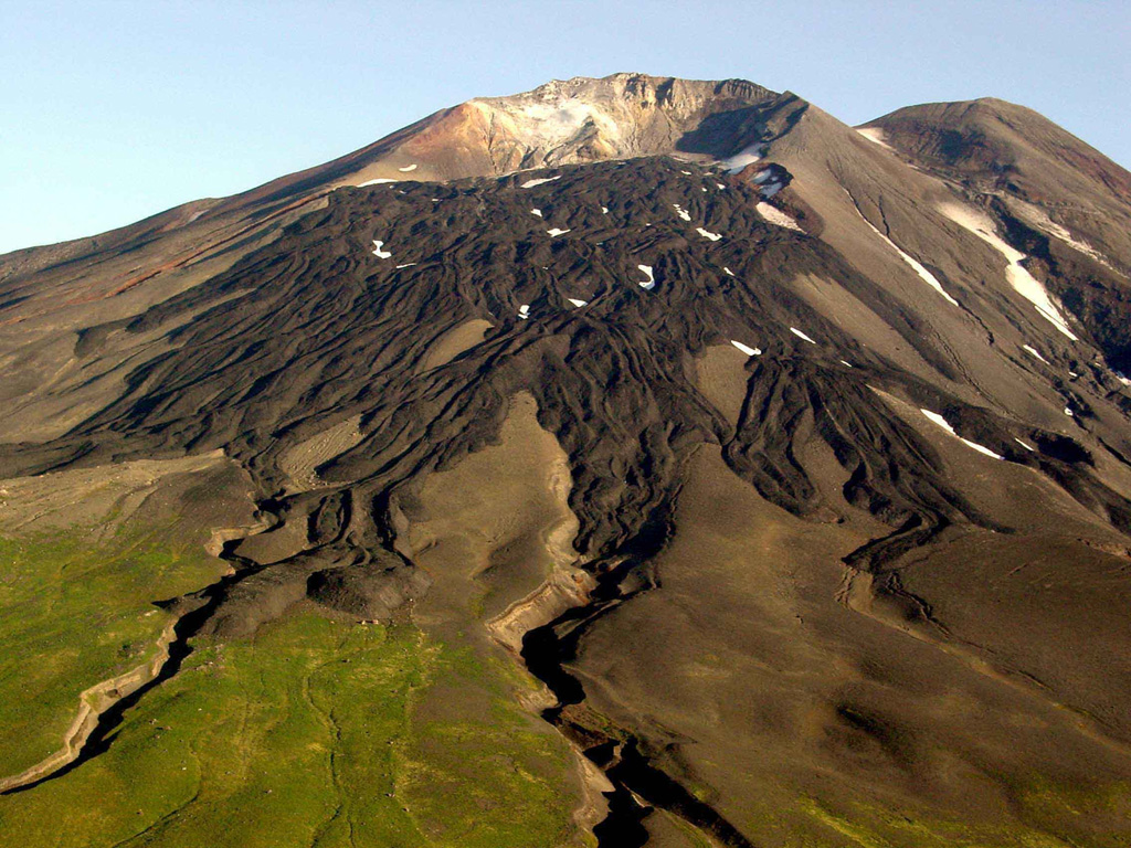 Gareloi in the western Aleutian Islands is seen here from the S. This photo shows lava flows with clear levees from a 1980s eruption. The 8 x 10 km diameter Gareloi Island consists of a stratovolcano with two peaks and a SE-trending fissure that formed during a 1929 eruption and extends  to the sea. Photo by Game McGimsey, 2003 (Alaska Volcano Observatory, U.S. Geological Survey).
