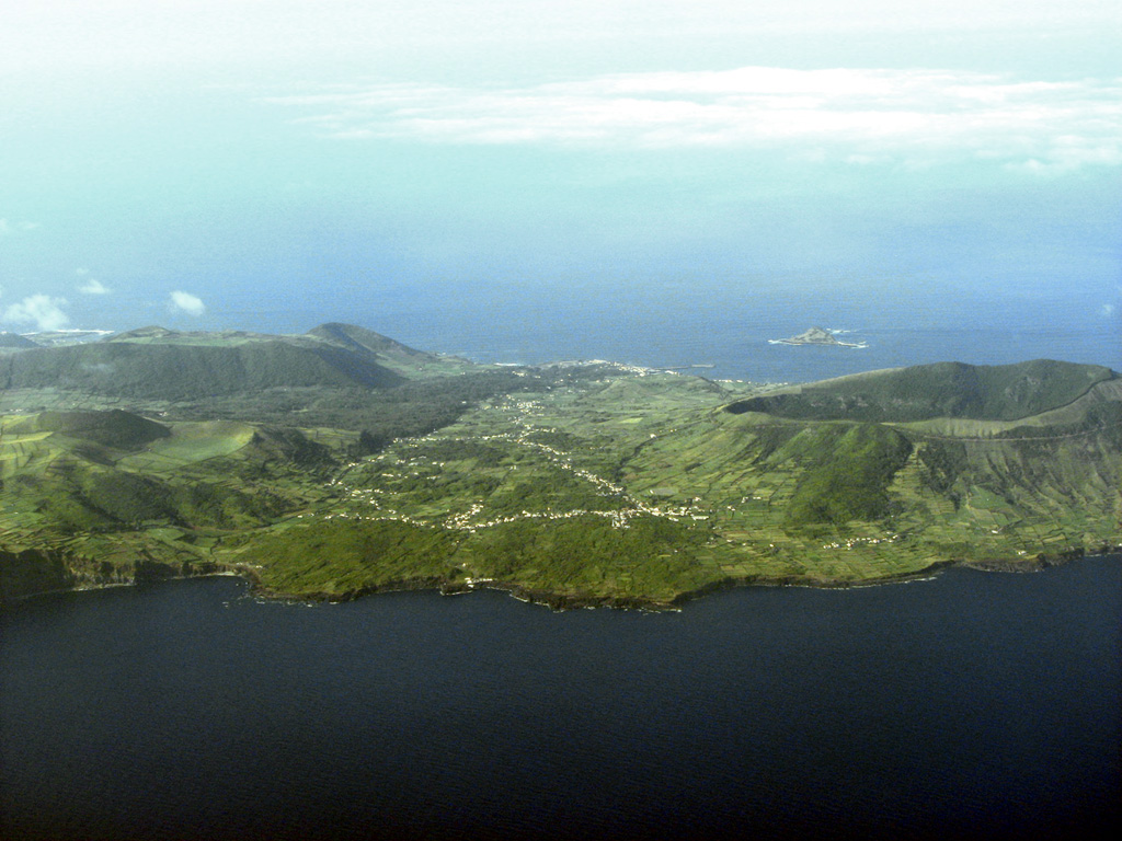 The south of Graciosa island is seen in this aerial view from the southwest. The village of Luz is at the center of the image. On the right (the southeast end of the island), is the 0.9 x 1.5 km Vulcão Central caldera, which formed between 60,000 and 11,000 years ago; the caldera rim forms the highest point of the 7 x 12 km island. The lava cave Furna Do Enzofre is situated in the southeastern part of the caldera, and exhibits fumarolic activity. Vegetated volcanic cones and part of the approximately 700,000 year old Serra das Fontes complex can be seen in the left of the photo. Photo by Angrense, 2007 (Wikimedia Commons).