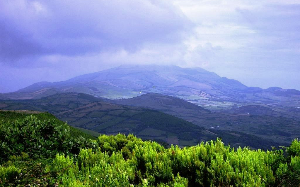 The Pico da Velha cone is seen in this view of the interior of the island of São Jorge. The linear island is 54 km long and only about 6 km wide at its widest point. This cone is one of many along a volcanic ridge down the axis of the island. Eruptions recorded since 1580 have produced lava flows that reached the ocean, and submarine eruptions were reported from vents off the southern and southwestern coasts. Photo by Luís A. da Silveira, 2007 (Wikimedia Commons).