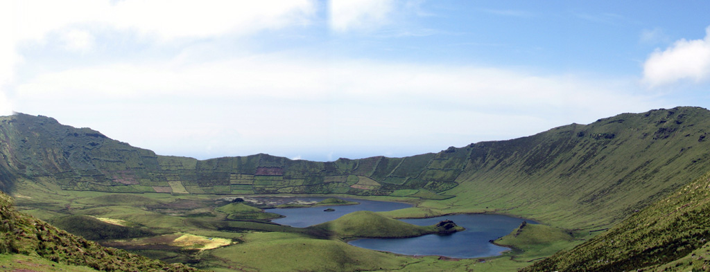 Agricultural fields line much of the walls of a 2-km-wide caldera on the northwest side of Corvo Island. The walls reach about 200 m above the caldera floor, which contains several small, vegetated cinder cones and two shallow lakes. The 4 x 6 km island is located at the NW end of the Azores archipelago, west of the Mid-Atlantic Ridge. The Vila do Corvo flank eruption is the youngest known activity, dated about 80,000 years ago; it produced a lava flow that reached the ocean on the southern tip of the island. Photo by Argense, 2007 (Wikimedia Commons).
