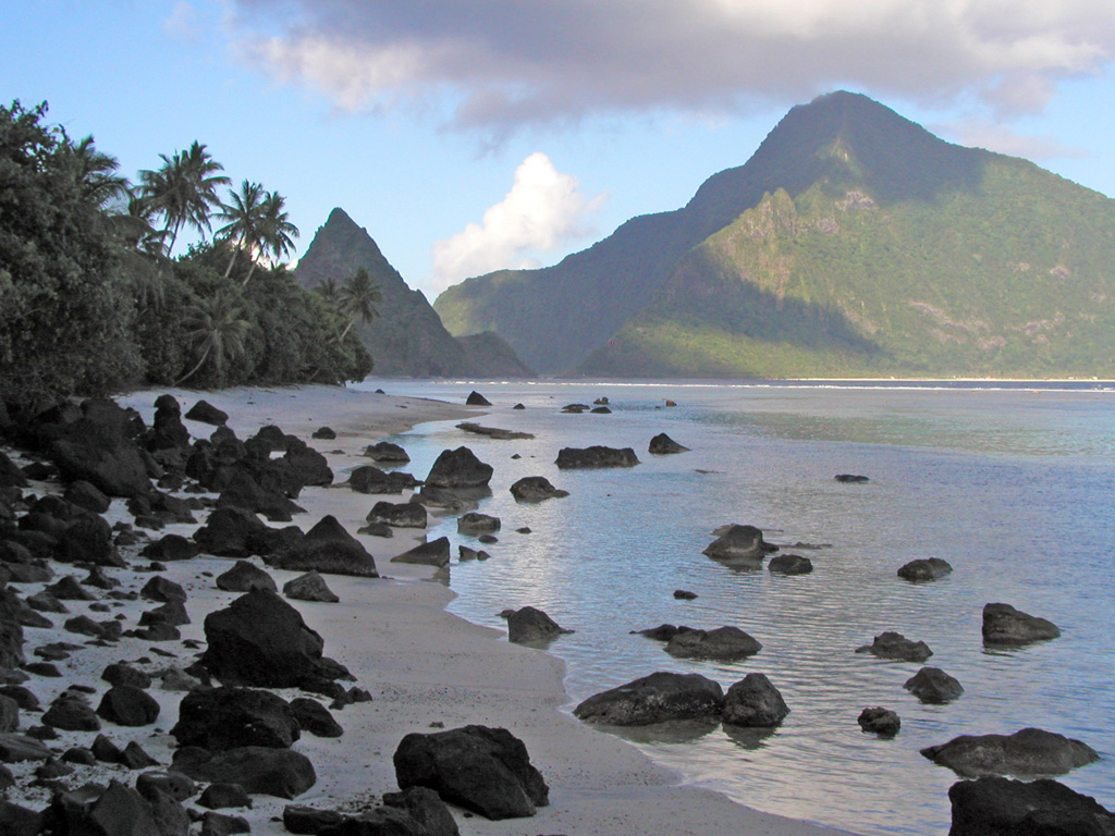 A narrow strait (just left of center) separates the two triangular islands of Ofu (left) and Olosega (right) in eastern Samoa. The islands are formed by two eroded, coalescing shield volcanoes. The narrow, steep-sided ridge forming the W side of Ofu Island is cut by volcanic dikes and an intrusive plug forms the sharp spire on Ofu Island to the left. A submarine eruption took place in 1866 at the far end of the two islands, 3 km SE of Olosega, along the ridge connecting Olosega with Ta'u Island. Photo by Peter Craig, 1995 (U.S. National Park Service).