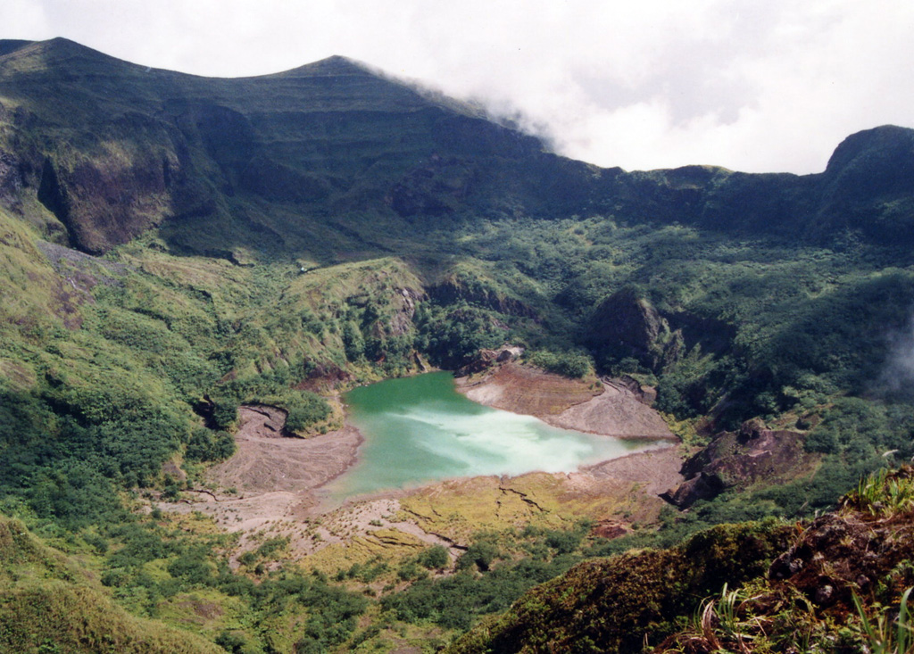 A shallow lake partially fills the summit crater of Awu volcano in this 1995 view.  Gunung Awu volcano, one of the deadliest in Indonesia, is cut by deep valleys that form passageways for lahars dissect the flanks of the 1320-m-high volcano.  Powerful explosive eruptions in 1711, 1812, 1856, 1892, and 1966 produced devastating pyroclastic flows and lahars that caused more than 8000 fatalities.   Photo by Kristianto, 1995 (Centre of Volcanology & Geological Hazard Mitigation, Volcanological Survey of Indonesia).