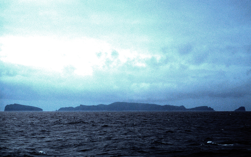 The isolated, uninhabited Antipodes Islands, seen here from the north, are located in the south Pacific, 770 km SE of New Zealand.  Volcanism has been dominantly pyroclastic, and the presence of well-preserved scoria cones suggests a Holocene age.  The most recent eruptions occurred on the cone forming Mount Galloway and Mount Waterhouse at the center of Antipodes Island.  Bollons Island, at the left, lies off the NE coast of the 4-km-wide main island.  Photo by Benjamin Hell, 2003 (wikimedia commons, http://creativecommons.org/licenses/by-sa/2.5/).