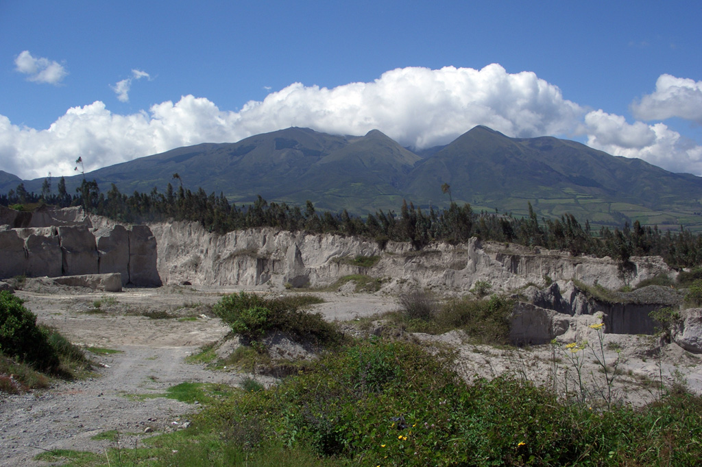 Part of the Chachimbiro volcanic complex, located about 25 km NW of the city of Ibarra, is seen from the south.  The late Pleistocene-to-Holocene, NNE-trending dacitic Chachimbiro-Pucará line of lava domes includes the Pitzantzi lava dome, which erupted about 5700 years ago, producing an ash deposit that extends to the NW.   Hot springs and thermal areas are present at the Chachimbiro complex. Quarries in the foreground are cut into deposits from the caldera-forming eruption of Cuicocha volcano.     Photo by Lee Siebert, 2006 (Smithsonian Institution).