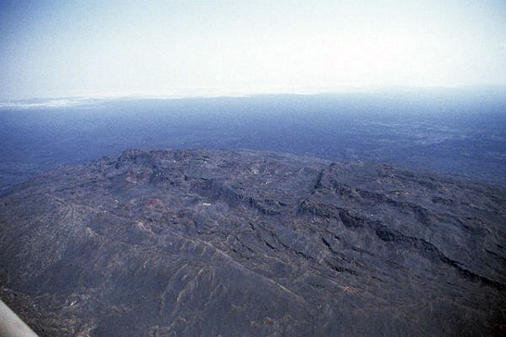 The summit region of Alu volcano is primarily composed of older basaltic lava flows. Major fumarolic activity is located on the numerous parallel faults, some of which have scarps up to 100 m high. Fissure vents west of the horst have fed silicic lava flows, and other fissures to the south have produced voluminous basaltic lava flows that extend north as far as Lake Bakili. Photo by Richard Roscoe, 2002.