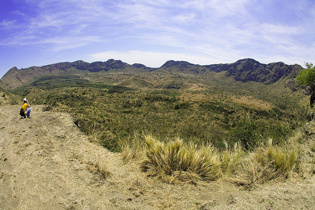 The caldera of Fentale volcano, also known as Fantale, is seen in a fish-eye lens view from the NE rim and has walls up to 500 m high. Welded pyroclastic flow deposits accompanied the 2.5 x 4.5 km summit caldera formation. The WNW-ESE-trending elliptical caldera has an orientation perpendicular to the Ethiopian Rift and post-caldera vents occur along the same orientation. Trachytic and obsidian lava flows were emplaced onto the caldera floor. More recent lava flows were erupted in the caldera and on its flanks in 1820. Photo by Tom Pfeiffer, 2008 (www.volcanodiscovery.com).