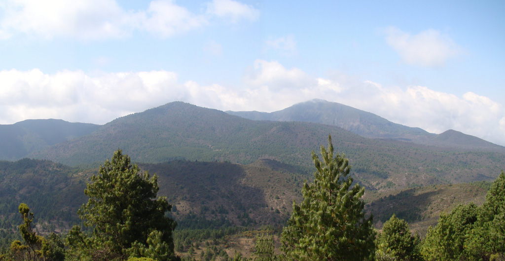 The summit of Rungwe is seen from WNW with the scarp resulting from edifice collapse in the background. At the left-center is a cone breached by a lava flow towards the S to SW (right). Rungwe volcano is the largest in the Karonga basin NW of Lake Malawi (Lake Nyasa) and is capped by a 4-km-wide caldera that is breached to the west. The caldera is largely filled by a series of youthful-looking uneroded and sparsely vegetated pumice cones, lava domes, and explosion craters. Photo by Karen Fontijn, 2008 (University of Ghent).