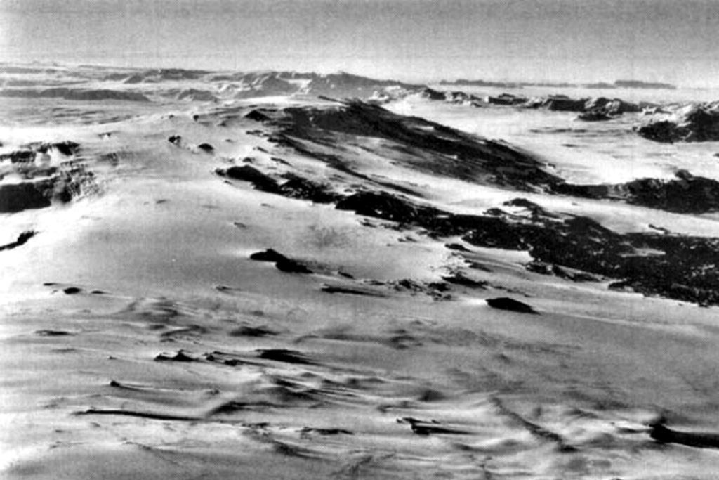 Mount Morning is seen in this aerial view from the NE. The summit contains an ice-filled 4.1 x 4.9 km caldera. Numerous flank lava domes and scoria cones formed along fissures on Hurricane Ridge across the NE flank to the middle right, and on the Riviera Ridge beyond on the N flank. Photo by U.S. Navy.