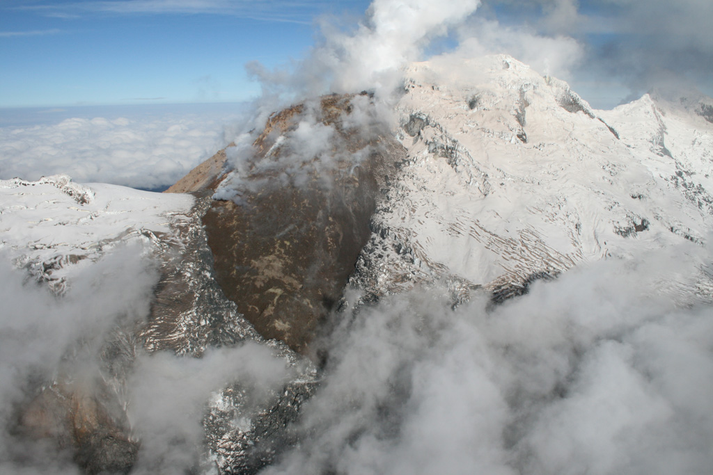 A dark, steaming lava seen from the east was emplaced during an eruption from Huila volcano that began in 2008.  Pico del Sur lies at the  left, with glacier-covered Pico Central at upper right and Pico Norte at far right.  The lava dome straddled the summit ridge and descended opposite sides of the volcano.  A major lahar in November 2008 swept down the Rio Paez, causing extensive damage.  Long-term ome growth and periodic ash emissions continued. Photo by Tom Pierson, 2010 (USGS, Cascades Volcano Observatory).