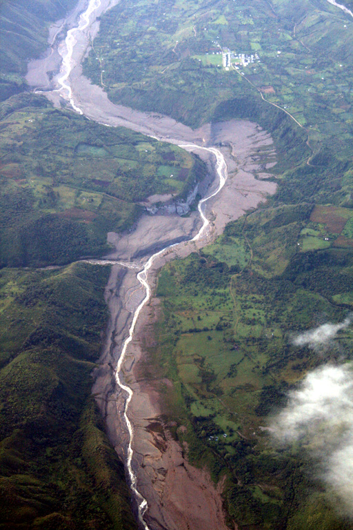 This aerial view of the Río Páez, with flow direction to the top, shows the path of the November 2008 lahars.  The village at upper right is Mesa de Caloto, SSW of Huila.  An eruption on November 20, 2008 destroyed part of the new lava dome, and hot material melted areas of the surrounding glacier and caused lahars in the Bellavista and Páez rivers, damaging infrastructure and destroying homes along the Río Páez.  Photo by Tom Pierson, 2010 (USGS, Cascades Volcano Observatory).