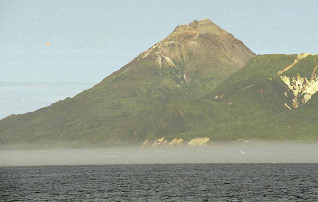 Ekarma with its summit lava dome rises above the sea with an older hydrothermally altered volcanic edifice to the right. The small 5 x 7.5 km island lies 8.5 km N of Shiashkotan Island in the central Kuriles. The summit lava dome was emplaced during the first historical eruption in 1776-79. Photo by Alexander Rybin, 2008 (SVERT).