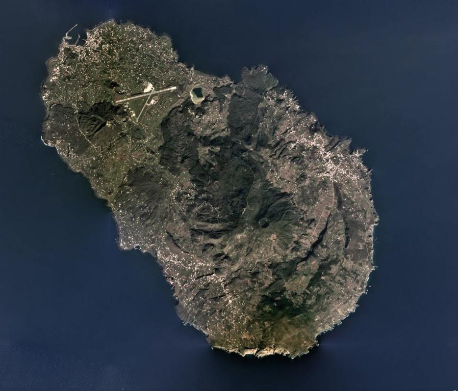 Pantelleria is a volcanic island 95 km west of Sicily and is composed of scoria cones, lava domes, lava flows, explosive eruption deposits, and calderas, with the Cinque Denti caldera rim visible in the right side of this 2019 satellite image (N is to the top). The 330 x 360 m crater near the center is within the summit of Monte Gibele, and lava flows with visible flow levees form the flanks. Montagne Grande is to the west (left) of the crater. Satellite image courtesy of Planet Labs Inc., 2019 (https://www.planet.com/).