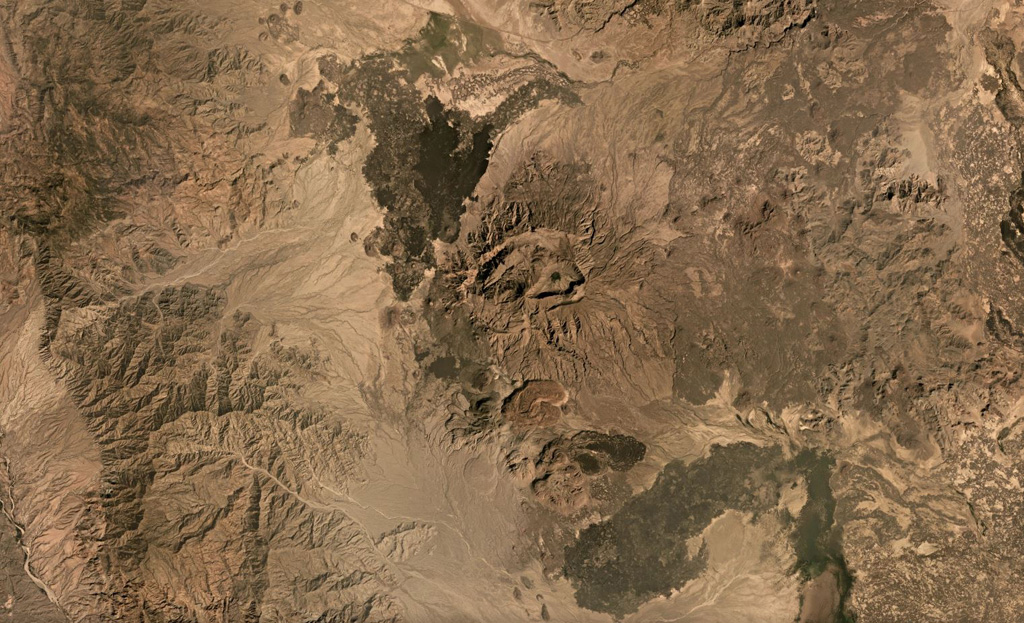 Ma’alalta, located along the western edge of the Afar Depression, has nested calderas that are seen in this December 2019 Planet Labs satellite mosaic (N is at the top), with ignimbrite deposits beyond the flanks. The larger caldera in the center of this image is about 7.5 km wide in the E-W direction. Darker basalt lava flow fields are visible, as well as thicker rhyolite lava flows and coulees to the south. Satellite image courtesy of Planet Labs Inc., 2019 (https://www.planet.com/).