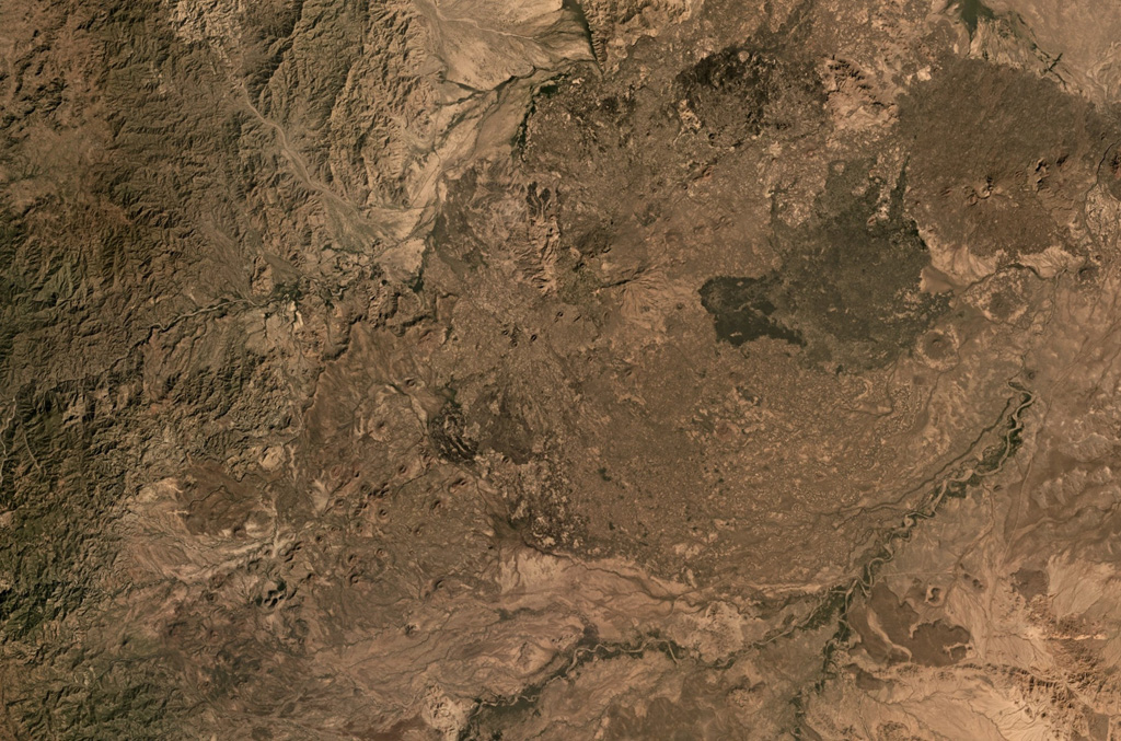 The Dabbayra shield volcano is shown in this December 2019 Planet Labs satellite image monthly mosaic (N is at the top; this image is approximately 58 km across). The complex has erupted along a NNE–SSW trend and covers an area of 30 x 60 km. The field largely comprises lava domes, scoria cones, and lava flows. Satellite image courtesy of Planet Labs Inc., 2019 (https://www.planet.com/).