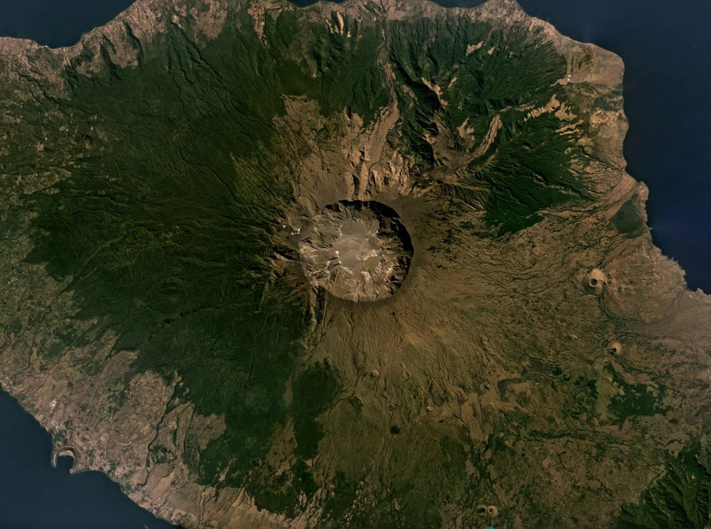 The 6-km-wide and 1-km-deep Tambora caldera that formed during the 1815 eruption is seen in this July 2019 Planet Labs satellite image mosaic (N is at the top). The 1815 eruption ejected around 41 km3 of magma and formed pyroclastic flows that reached the sea on all sides of the 60-km-wide volcanic peninsula of Sumbawa Island, triggering a tsunami. Satellite image courtesy of Planet Labs Inc., 2019 (https://www.planet.com/).