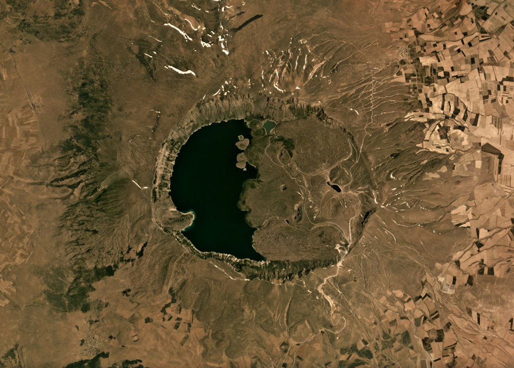 The eastern half of the 8.5 × 7 km Nemrut Dagi summit caldera is partially filled with lava flows, phreatomagmatic eruption deposits, and lava domes, and the western half is filled with a lake that is seen in this June 2019 Planet Labs satellite image monthly mosaic (N is at the top). The surrounding area contains ignimbrite deposits, tephra, lava domes, and lava flows. Satellite image courtesy of Planet Labs Inc., 2019 (https://www.planet.com/).