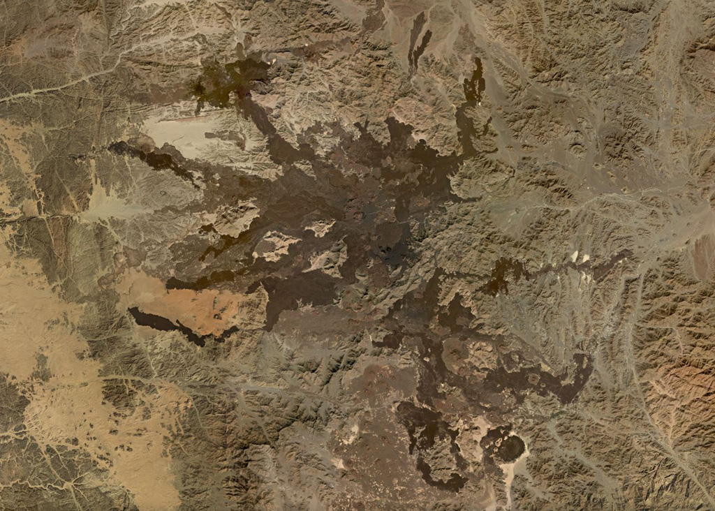 The Harrat Lunayyir volcanic field contains around 50 identified craters with numerous lava flows seen in this November 2019 Planet Labs satellite image monthly mosaic (N is at the top; this image is approximately 89 km across). The scoria cones contain summit craters and many experienced flank collapse or rafting during the eruptions, resulting in horseshoe-shaped craters. The youngest lavas occur in the central part of the field and cover 25 km2. Satellite image courtesy of Planet Labs Inc., 2019 (https://www.planet.com/).