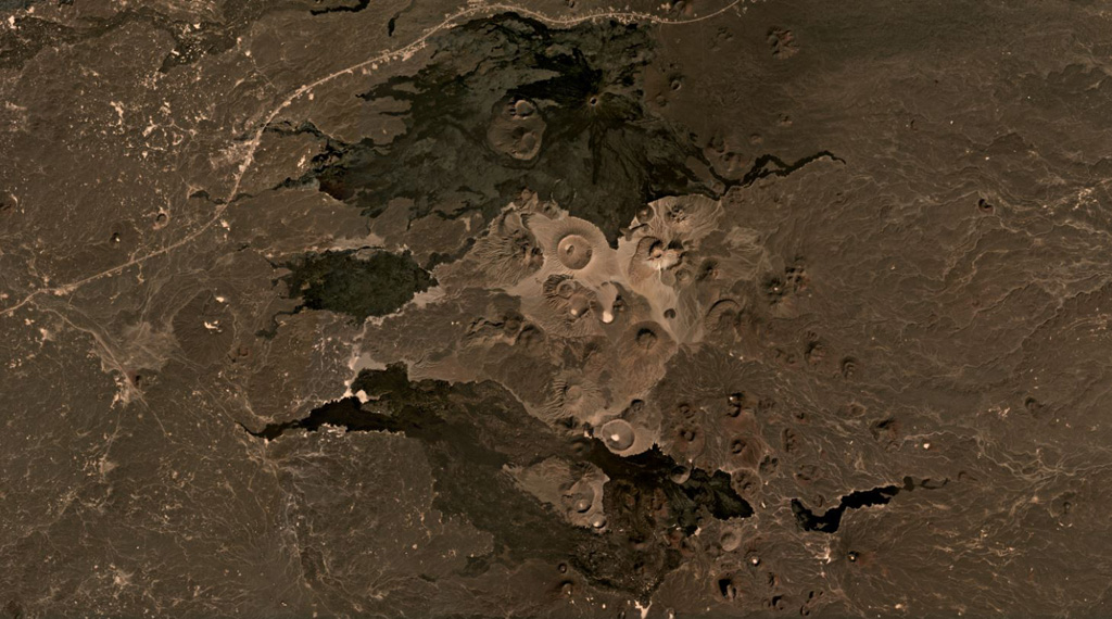 The central area of the 14,000 km2 Harrat Khaybar volcanic field is shown in this December 2020 Planet Labs satellite image monthly mosaic (N is at the top; this image is approximately 49 km across). This area contains tuff rings and maars from phreatomagmatic activity and scoria cones, with some more recent lava flows. The larger light-colored crater near the center is Jabal Bayda, and the cone that produced the black lava flows to the north is Jabal Qidr. Satellite image courtesy of Planet Labs Inc., 2020 (https://www.planet.com/).
