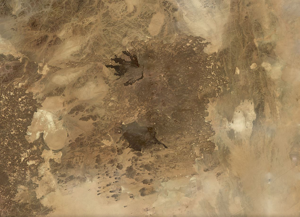 The roughly 6,000 km2 Harrat Kishb volcanic field is shown in this November 2019 Planet Labs satellite image monthly mosaic (N is at the top; this image is approximately 180 km across). The field is comprised of scoria cones, tuff rings, maars, lava domes, and flows. Along the western edge of the lower black lava flow field is the Al Wahbah maar, one of the largest in the Arabian Peninsula at 2.3 km wide. Satellite image courtesy of Planet Labs Inc., 2019 (https://www.planet.com/).