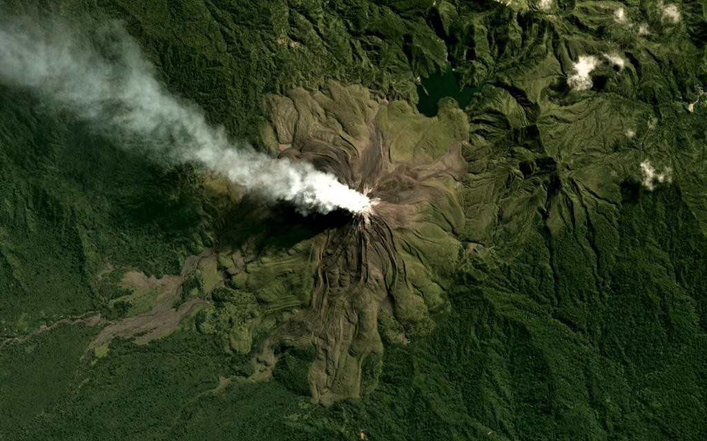 The flanks of Bagana are composed of radial lava flows that erupted from a central summit crater where a gas plume is emitting and dispersing NW, visible in this June 2019 Planet Labs satellite image monthly mosaic (N is at the top; this image is approximately 12 km across). At 2.5 km NW from the crater is a lava dome, and to the NE is the eroded Reini cone. Satellite image courtesy of Planet Labs Inc., 2018 (https://www.planet.com/).