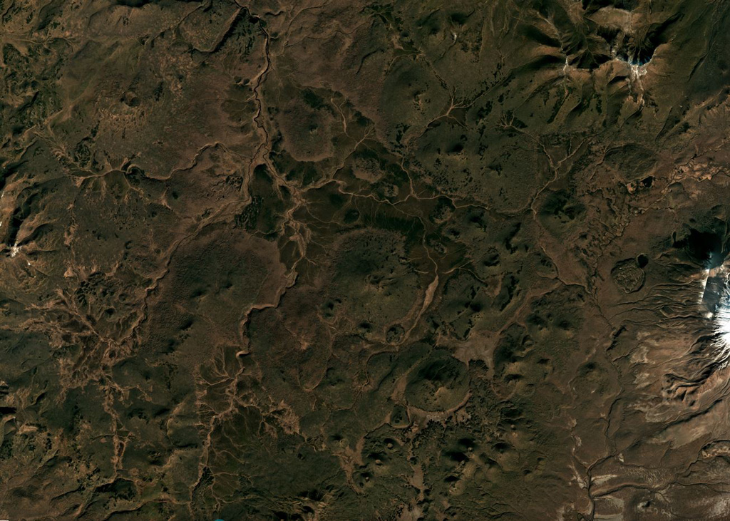 Cones of the Olkoviy Volcanic Group are shown in this October 2018 Planet Labs satellite image monthly mosaic (N is at the top; this image is approximately 30 km across). The group consists of cones and lava flows, with Olkoviy cone in the center of the image and the cone immediately SE is Plosky. The western flank of Khodutka is to the E and the eroded Krugliy cone is in the NE corner. Satellite image courtesy of Planet Labs Inc., 2018 (https://www.planet.com/).