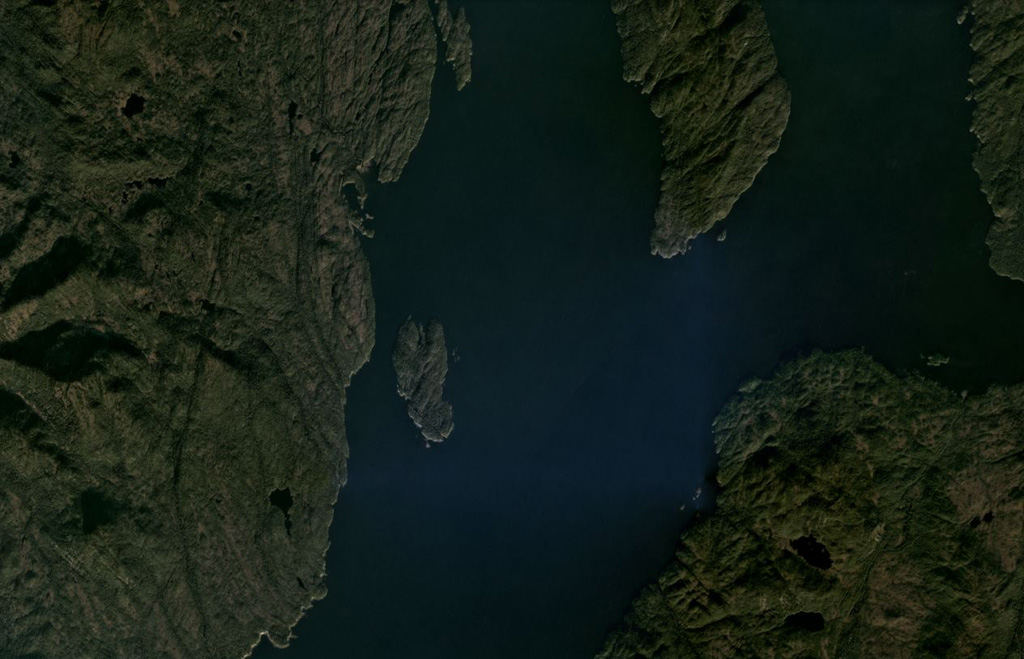 Scoria cones and columnar-jointed lava flows of the Behm Canal-Rudyerd Bay volcanic field occur on either side of Behm Canal (down the center of this image), shown in this October 2020 Planet Labs satellite image monthly mosaic (N is at the top; this image is approximately 20 km across). The majority of outcrops have been found on Revillagigedo Island (left), and additional features are on Rudyerd Island (near the center). Satellite image courtesy of Planet Labs Inc., 2020 (https://www.planet.com/).