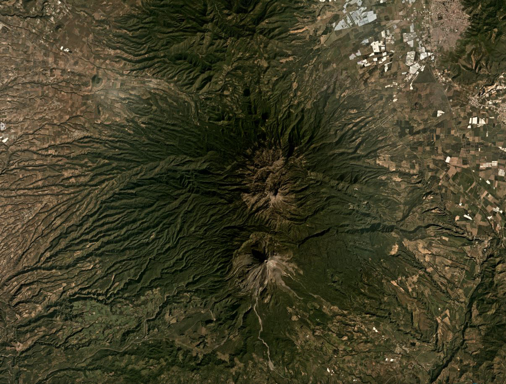 The Colima volcanic complex has two main edifices, the northern Nevado de Colima and the active Volcán de Colima to the south, both in the center of this December 2019 Planet Labs satellite image monthly mosaic (N is at the top; this image is approximately 44 km across). The active cone formed within a 5-km-wide flank collapse scarp, that produced a debris avalanche to the south, one of at least nine collapse events during the past 45,000 years. Satellite image courtesy of Planet Labs Inc., 2019 (https://www.planet.com/).