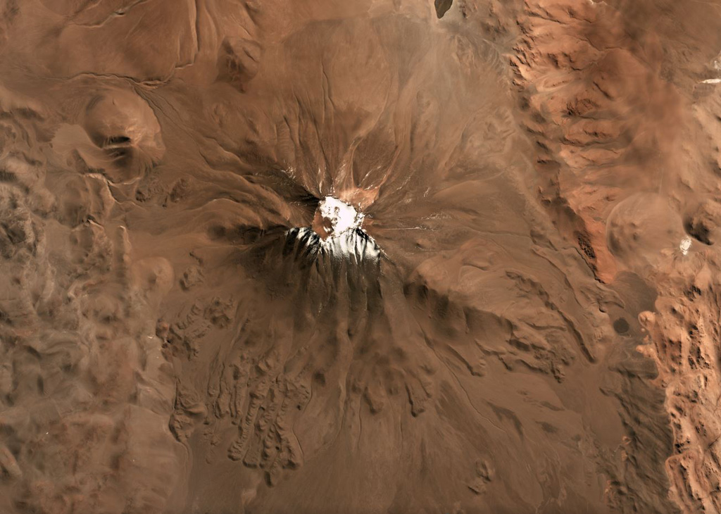 Aracar volcano in Argentina has a 1.5-km-wide summit crater in the center of this May 2019 Planet Labs satellite image monthly mosaic (N is at the top; this image is approximately 22 km across). Lobate lava flows with pressure ridges are exposed along the lower southern flanks, and lava flows have been emplaced around topographic highs on the W, E, and S. Satellite image courtesy of Planet Labs Inc., 2019 (https://www.planet.com/).