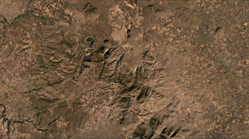 The Göllü Dag volcanic complex in Turkey is shown in this August 2019 Planet Labs satellite image monthly mosaic (N is at the top; this image is approximately 35 km across). The 10-12-km-wide complex formed through the coalescence of at least ten rhyolite domes, with scoria cones, lavas, ignimbrites, and over 25 vents surrounding them. The Aci Gölü maar contains the lake to the upper left, with several scoria cones nearby. The domes are in a rough southeast trend from this maar and have erosion gullies on their flanks. Satellite image courtesy of Planet Labs Inc., 2020 (https://www.planet.com/).