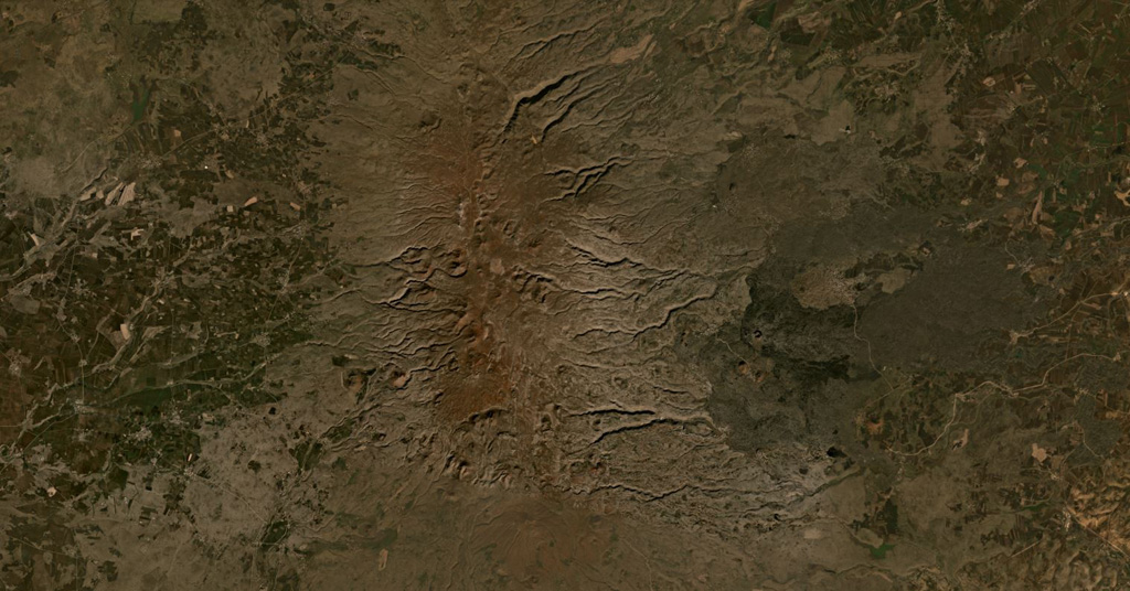 The Karaca Dag/ Karacadağ shield volcano covers around 10,000 km2 in Turkey, with the more recent N-S plateau of scoria cones and lava flows down the center of this January 2020 Planet Labs satellite image monthly mosaic (N is at the top; this image is approximately 63 km across). A younger group of lava flows erupted from vents on the eastern flank, appearing darker with the vents visible. Satellite image courtesy of Planet Labs Inc., 2021 (https://www.planet.com/).