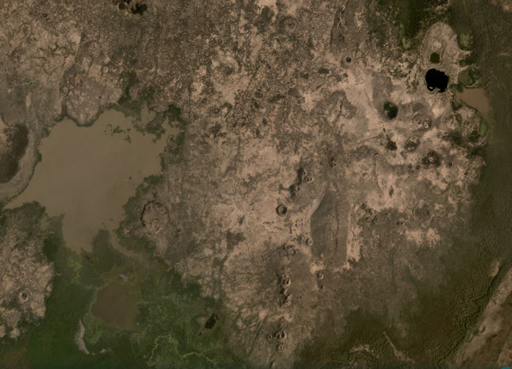 The Liado Hayk volcanic group contains maars and scoria cones visible across this February 2021 Planet Labs satellite image monthly mosaic (N is at the top; this image is approximately 13.5 km across). A cluster of maar craters is in the top right of this image, with some containing lakes, the largest of which is the darker-colored 600-m-wide lake. There are several linear groups of scoria cones and partly-buried lava flow fields around them. Satellite image courtesy of Planet Labs Inc., 2021 (https://www.planet.com/).