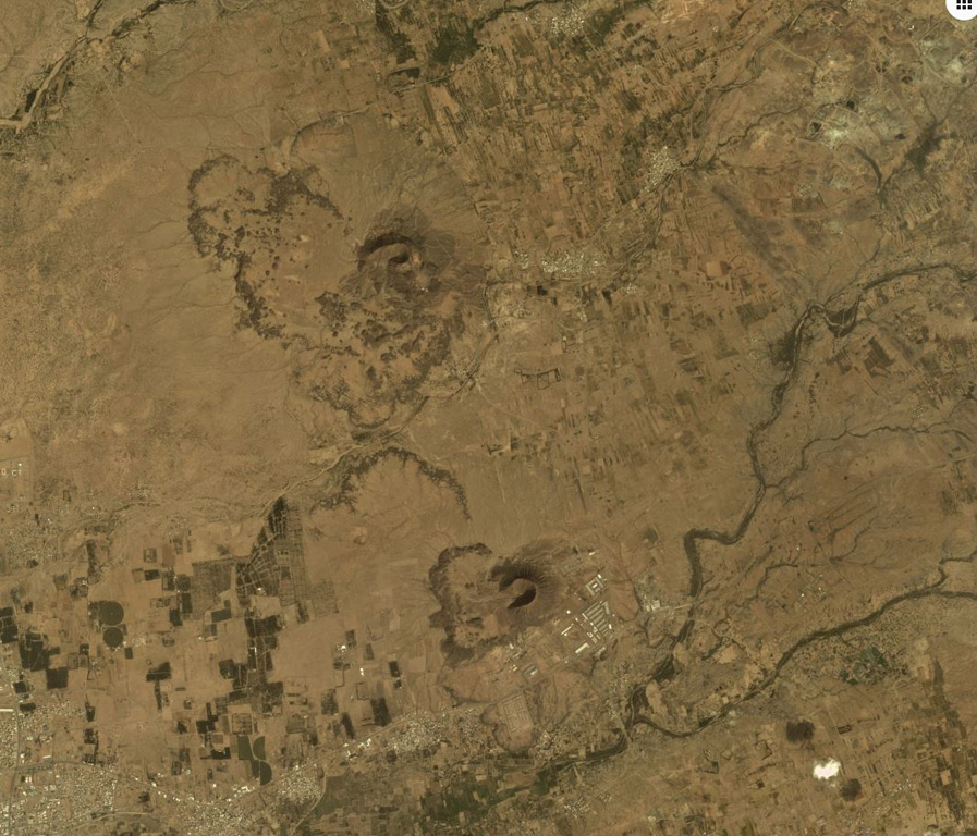 Two scoria cones of the Jabal Yar volcanic center in SW Saudi Arabia are sown in this December 2019 Planet Labs satellite image monthly mosaic (N is at the top; this image is approximately 19 km across). There are three groups of cones and this is the northernmost 'Ukwatain group. Both cones underwent flank collapse or rafting during their eruptions and now open towards the W. Lava flow boundaries are visible on the western side of both cones. Satellite image courtesy of Planet Labs Inc., 2019 (https://www.planet.com/).