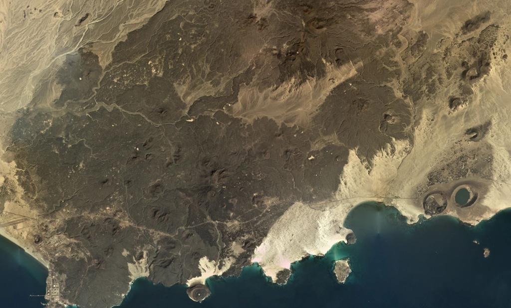 The Bir Borhut volcanic field in southern Yemen is shown in this December 2019 Planet Labs satellite image monthly mosaic (N is at the top; this image is approximately 26 km across). The At-Tabâb maar is SE of the lava field along the coastline next to a tuff ring. Cones have formed throughout the darker lava field. Satellite image courtesy of Planet Labs Inc., 2019 (https://www.planet.com/).