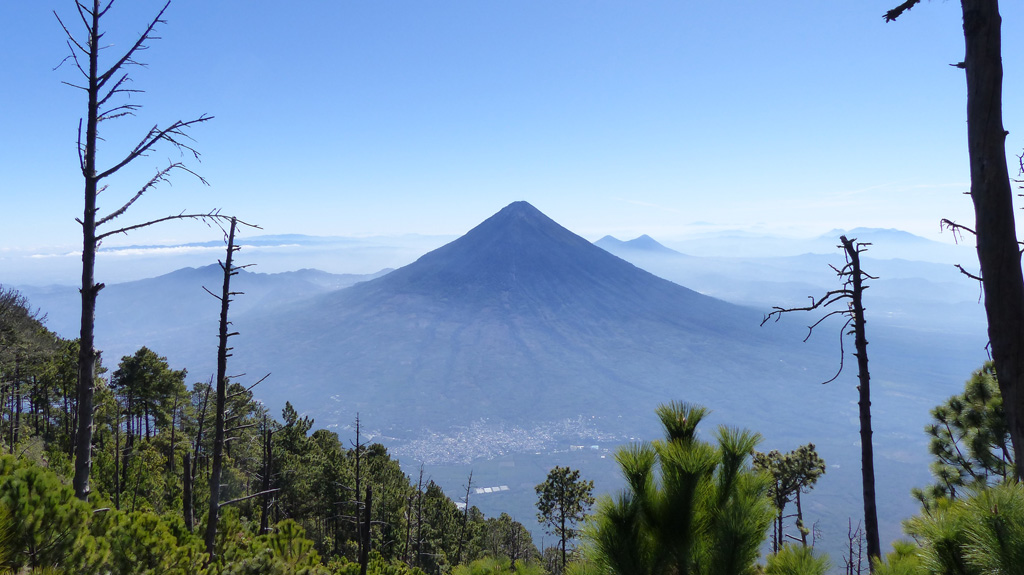 Volcán de Agua is seen here from the E flank of Volcán Acatenango. The peaks of Cerro Grande and Volcán Pacaya are visible behind Agua (right) and the town of Alotenango is below it. Photo by Ailsa Naismith, 2020.