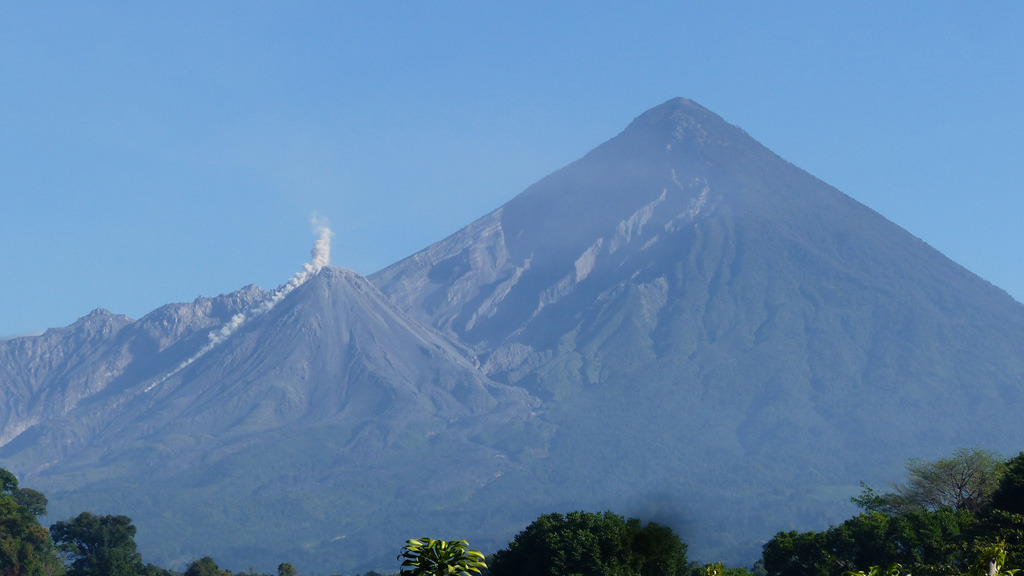 A rockfall descends the S flank of the Caliente dome of the Santiaguito dome complex at Santa Maria volcano on 28 February 2020, causing a small ash plume to rise above it. The Santa Maria edifice is behind and just right of the dome, with the large 1902 crater wall extending down its SW flank. Photo by Ailsa Naismith, 2020.