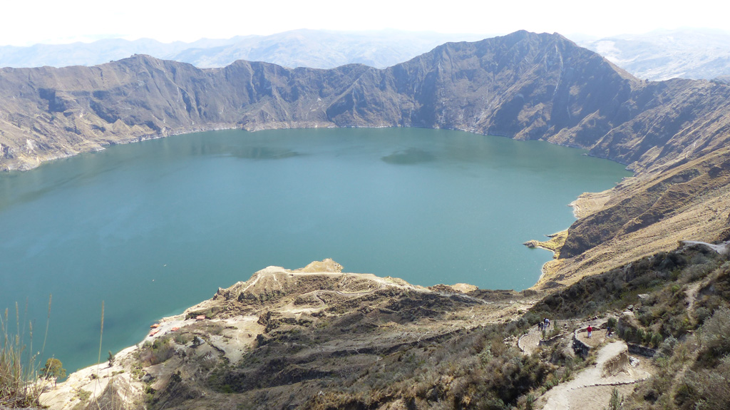 The 3-km-wide Quilotoa caldera resulted from several collapse events and contains a turquoise lake approximately 250 m deep. Intrusions and lava domes are exposed within the crater walls, with the largest being 1.3 km diameter and 400 m high in the ESE wall visible on the far side of this 2015 photo. Behind the caldera rim is the Interandean Valley. Photo by Ailsa Naismith, 2015.