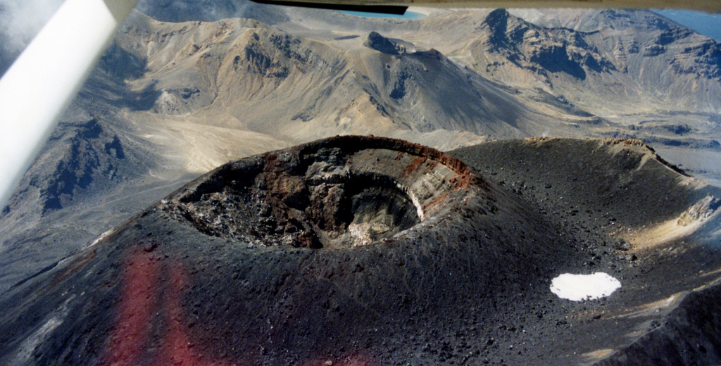 The scoria cone within the summit crater of Tongariro’s Ngāuruhoe cone formed during the 1954-75 eruptions. The majority of the cone formed during 1954-55 with the red unit at the top (along the right rim of the crater in this view) forming during the 1974-75 eruption. The outer crater rim is to the right. The northeastern part of the Tongariro volcanic complex is in the background, with Blue Lake visible at the top of the photo. Photo by John A Krippner, 1995-1996.